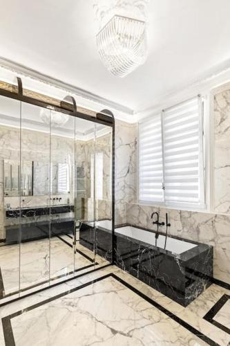 une grande salle de bains avec baignoire et lustre dans l'établissement Spectacular 3BR Luxury Residence - Arc de Triomphe, 264m2, à Paris