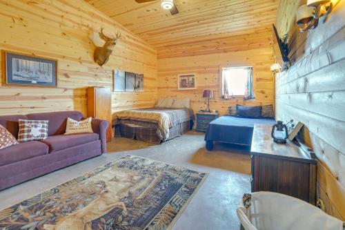 Dormitorio en cabaña de madera con cama y sofá en Hot Tub and Fire Pit Family Retreat in South Dakota, en Fedora