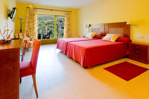 a bedroom with a large red bed and a desk at Mirador de La Portilla in Jarandilla de la Vera