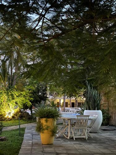 a patio with a table and chairs under a tree at Aquarius Club in Watamu
