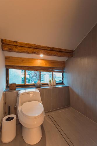 a bathroom with a white toilet and a window at Infini House in Dali