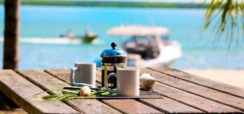 a picnic table with a coffee maker and mugs on it at Crab Claw Island in Bynoe Harbour