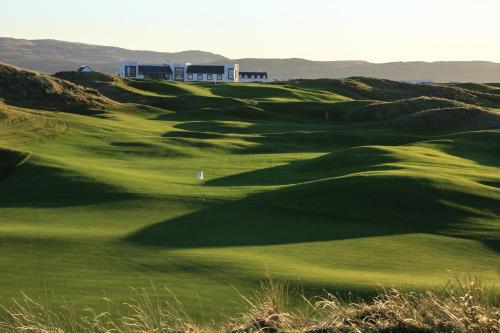 a green golf course with a building in the background at Another Place, The Machrie in Port Ellen