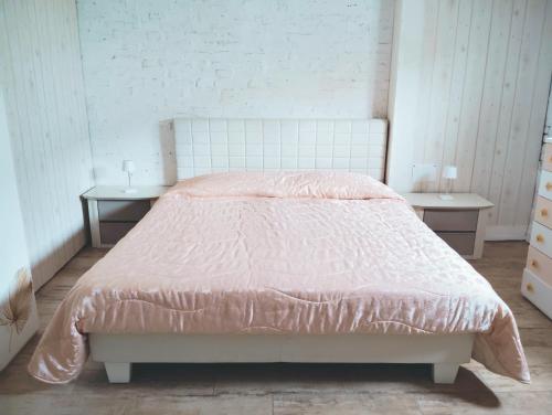 a bedroom with a bed with a pink comforter and two tables at Valle Rubicone in Gatteo
