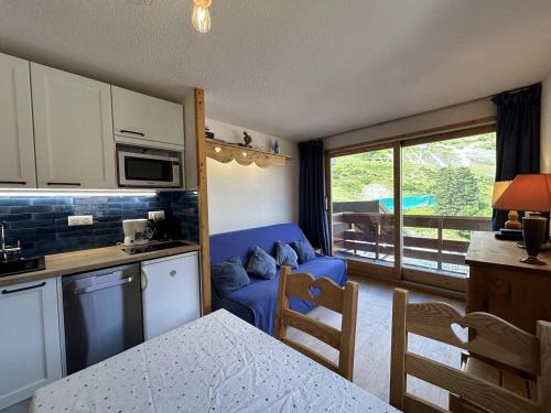Il comprend une cuisine et un salon avec un canapé bleu. dans l'établissement Charmant 2 pièces à Méribel avec balcon et WIFI, pieds des pistes - FR-1-355-260, à Les Allues