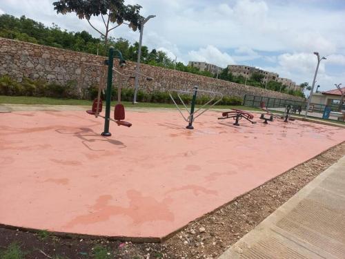 a playground with a bunch of swings on a pink ground at Pool Side Punta Cana in Punta Cana