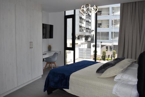 キトにあるHarmony Staysのベッドと机と窓のある寝室