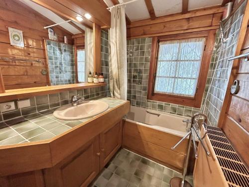 La salle de bains est pourvue d'un lavabo, d'une baignoire et d'une fenêtre. dans l'établissement Chalet 6-8 pers, 4 chambres, proche remontées, parking - FR-1-597-182, à Megève