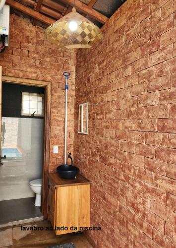 a bathroom with a brick wall and a toilet at Recanto do Bem-Te-Vi in Olímpia