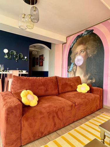 a living room with a couch with a painting of a woman with a mask at Appartement Pop Art in Louviers