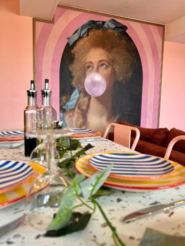 Une femme avec une gomme rose dans la bouche à une table dans l'établissement Appartement Pop Art, à Louviers