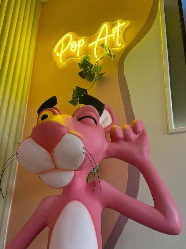 a statue of a pinkanimal in front of a neon sign at Appartement Pop Art in Louviers