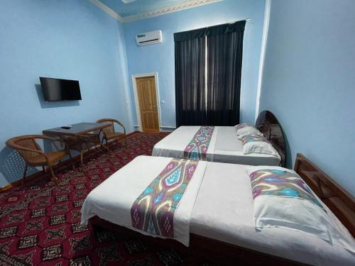 una habitación de hotel con dos camas y una mesa en Shukrona Guest house, en Bukhara