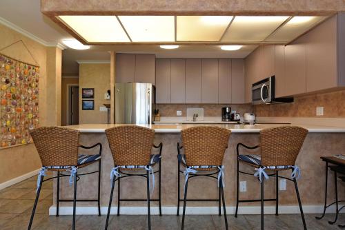 a kitchen with three bar stools and a counter at Maui Eldorado Condo J100 in Kaanapali