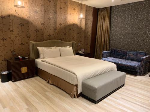 a bedroom with a large bed and a chair at Aquarius Motel in Taichung