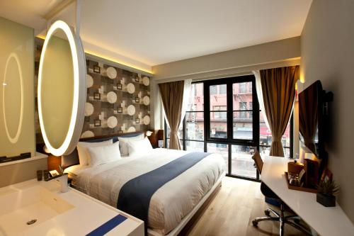 Schlafzimmer mit einem Bett, einem Waschbecken und einem Spiegel in der Unterkunft NobleDEN Hotel in New York