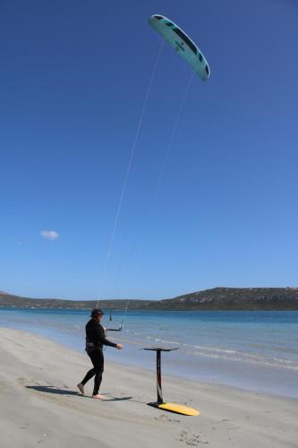 a man flying a kite on the beach at Downwind - Visit Langebaan in Langebaan