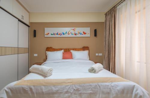 a bedroom with a large white bed with towels on it at Exquisite Condo with Free parking Gym and Pool in Nairobi