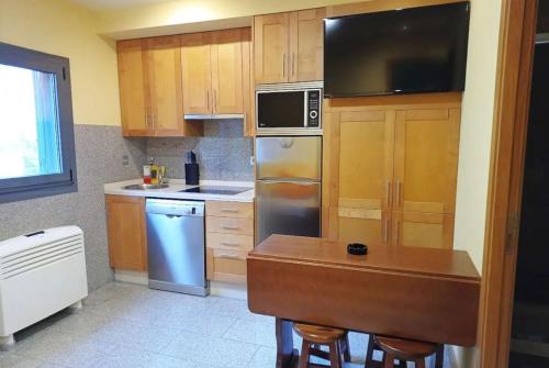 Una cocina con gabinetes de madera y electrodomésticos de acero inoxidable. en Apartamentos Ababides Playa, en Baiona