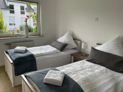 two beds in a room with a window at Ferienwohnung Sieben, Zentral gelegene mit Tiefgaragenstellplatz in Bad Oeynhausen