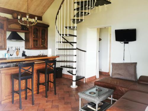 a living room with a kitchen and a spiral staircase at Svenceles 25 sodyba Namas su pirtimi ir krantine in Svenele