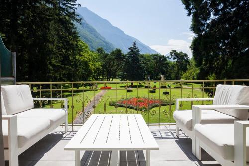 a patio with white furniture and a view of a garden at Grand Hotel des Bains in Lavey-les-Bains