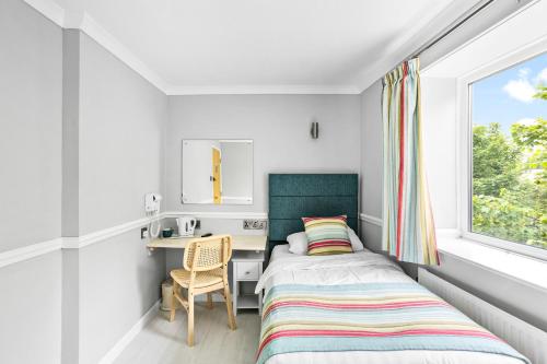 a bedroom with a bed and a desk and a window at Waters Edge Hotel Torquay in Torquay