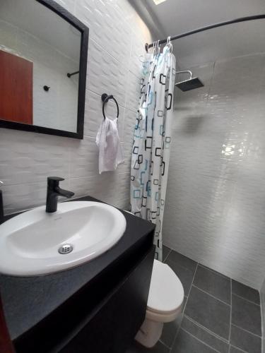 a bathroom with a sink and a toilet and a mirror at Casahotelnapoles in Calarcá