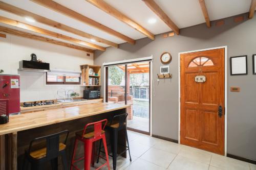 a kitchen with a wooden counter and stools at Pucón Rec-Lodge Cabaña Carpintero in Pucón