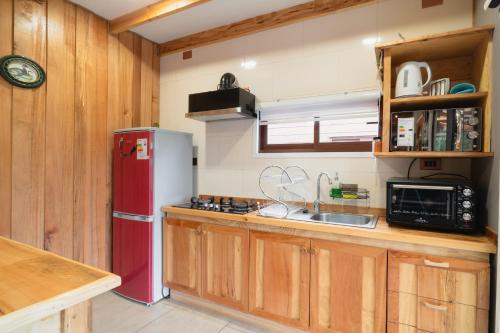 a kitchen with a red refrigerator and wooden cabinets at Pucón Rec-Lodge Cabaña Carpintero in Pucón
