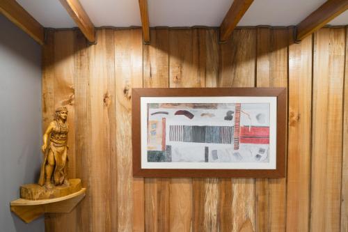 a framed picture on a wooden wall with a statue at Pucón Rec-Lodge Cabaña Carpintero in Pucón
