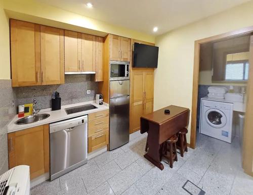 cocina con armarios de madera, fregadero y lavavajillas en Apartamentos Ababides Playa, en Baiona