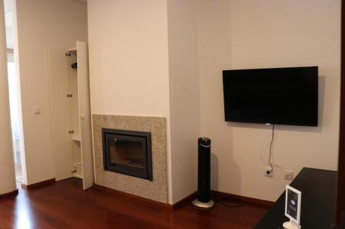 a living room with a fireplace and a flat screen tv at Estudio Metro heroismo in Porto