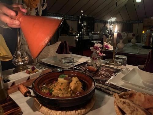 a person holding up a drink in a bowl of food at Sahara Zen Luxury Camp in Merzouga