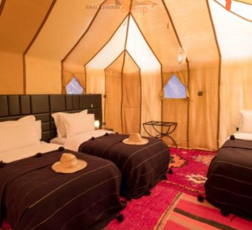 two beds in a tent with hats on them at Sahara Zen Luxury Camp in Merzouga
