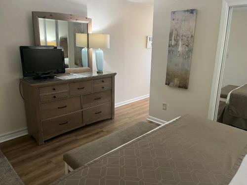 1 dormitorio con tocador, TV y espejo en Summer Sands - 202 by Sea Scape Properties, en Wrightsville Beach