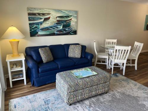 a living room with a blue couch and a table at Summer Sands - 207 by Sea Scape Properties in Wrightsville Beach
