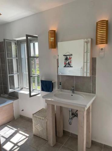 a bathroom with a white sink and two windows at Rusztikus ház Mindszentkálla in Mindszentkálla