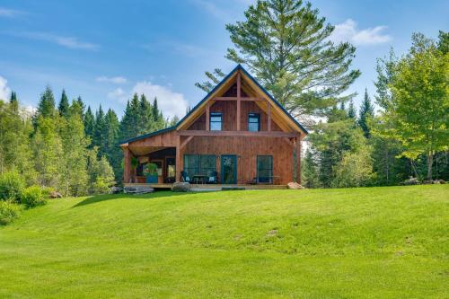 a house on a hill with a green field at Fire Pit and Views Pet-Friendly Vermont Cabin in Craftsbury