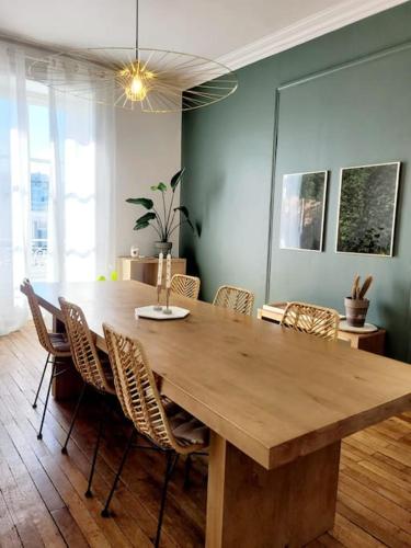une grande table en bois dans une pièce avec des chaises dans l'établissement Le Botanik - Haussmannien près jardin des plantes, à Nantes