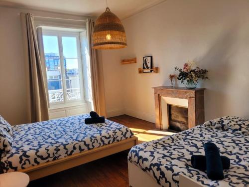 - une chambre avec 2 lits, une cheminée et une fenêtre dans l'établissement Le Botanik - Haussmannien près jardin des plantes, à Nantes