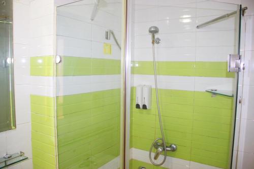 a bathroom with a shower with green and white tiles at 7Days Inn Chengdu Wuda Garden in Chengdu