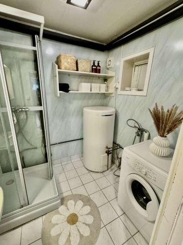 a small bathroom with a washing machine and a shower at Aurora Stay- Aurora garden Apartment in Tromsø