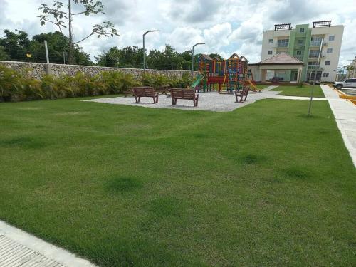 a park with benches and a playground in the grass at Pool Sensation Punta Cana in Bávaro