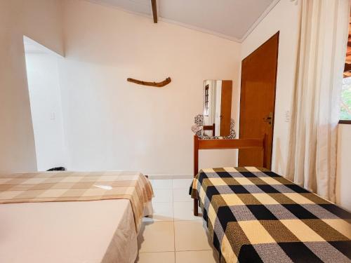 a bedroom with two beds and a window at Pousada Donalu - Ótima Localização in Vale do Capao