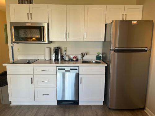 a kitchen with white cabinets and a stainless steel refrigerator at Summer Sands - 307 by Sea Scape Properties in Wrightsville Beach