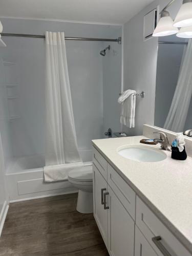 a white bathroom with a sink and a toilet at Summer Sands - 307 by Sea Scape Properties in Wrightsville Beach