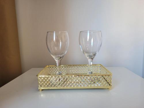 two wine glasses on a gold stand on a table at Apê aconchegante no Centro da cidade - Cantinho da Bia 2 in Miguel Pereira