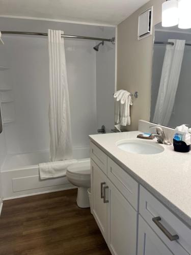 a white bathroom with a toilet and a sink at Summer Sands - 401 by Sea Scape Properties in Wrightsville Beach
