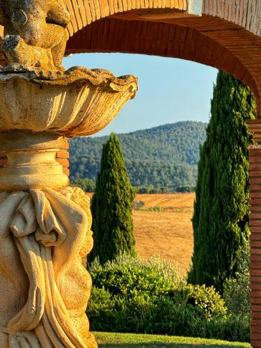 a stone archway with a view of a field and trees at Agriturismo Il Raduno - Max Lelli in Marsiliana